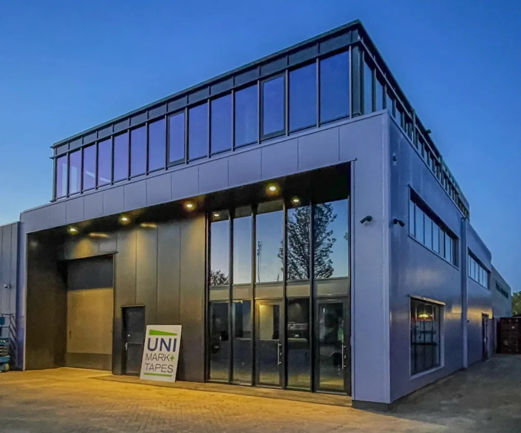 Een gemoderniseerde bedrijfsloods op een industrieterrein in Oud-Beijerland, met een nieuw kantoor en uitgebreide dakopbouw. De gevels zijn bekleed met moderne sandwichpanelen, aluminium kozijnen en geïsoleerde beglazing, wat zorgt voor een strakke, energiezuinige uitstraling.